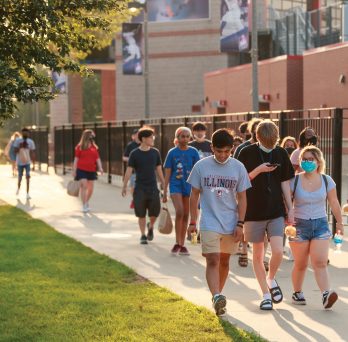 Students walking down a sidewalk on campus
                  