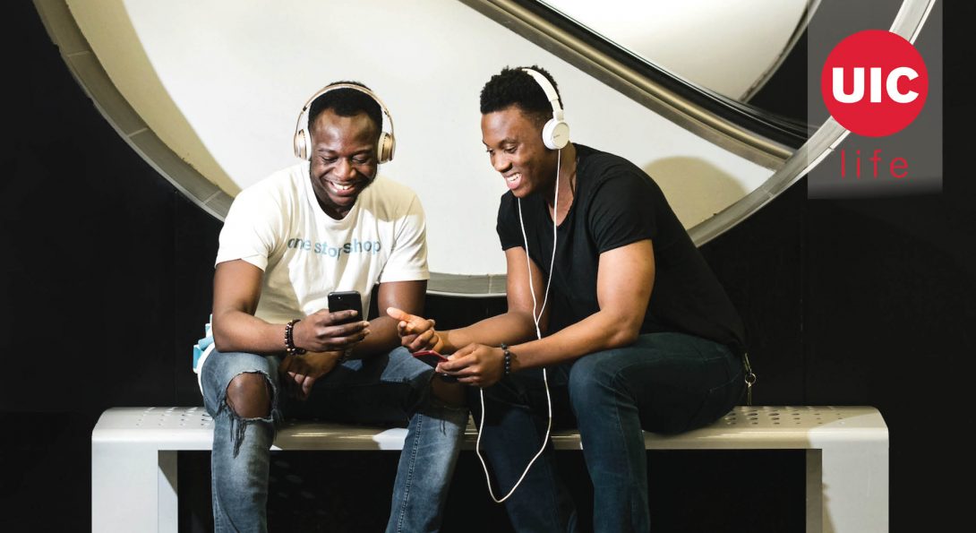 Two male students smiling and listening to music on headphones.