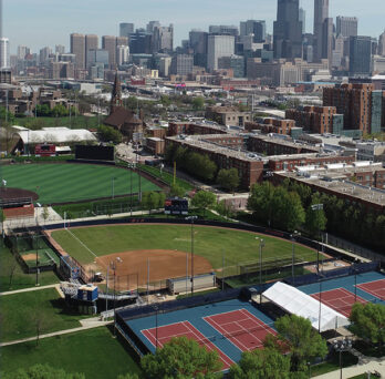 Outdoor green athletic fields at UIC campus against background of Chicago skyline
                  