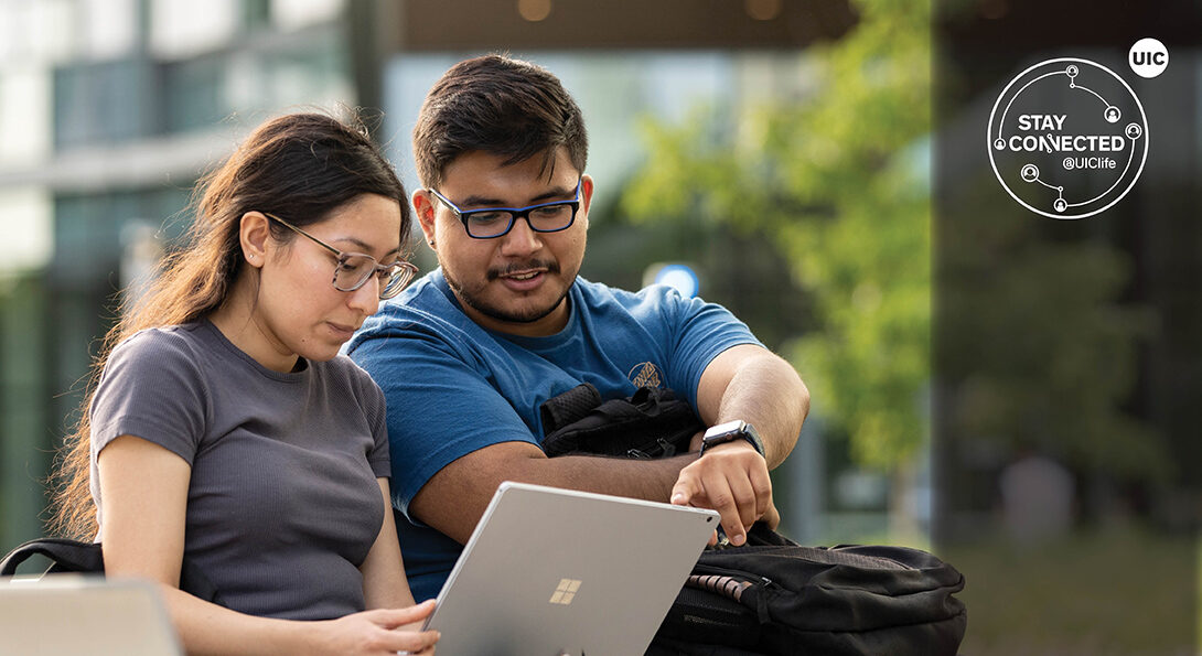 Male and female student working on a laptop outdoors.