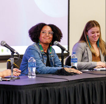 Three women of various ethnicities on a panel.
                  