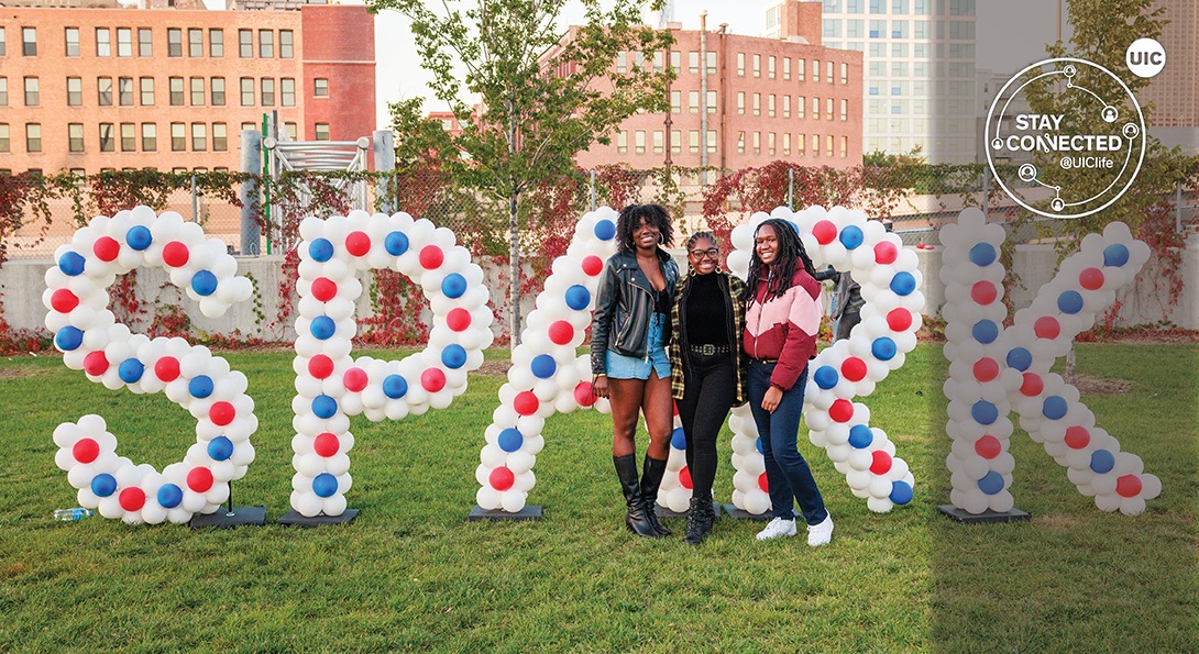 UIC students in front of large SPARK balloons, City of Chicago in background