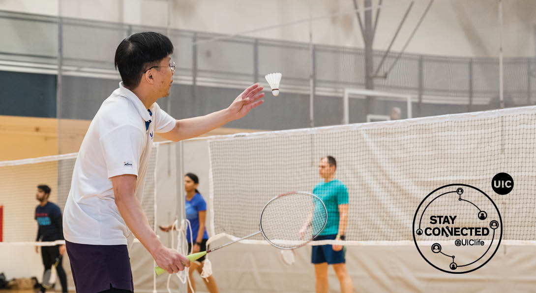 UIC student preparing a badminton serve with 3 students in the background
