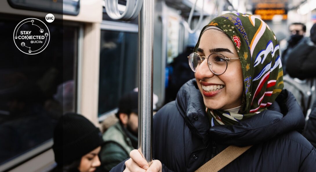 Female student holds bar while commuting on a bus.