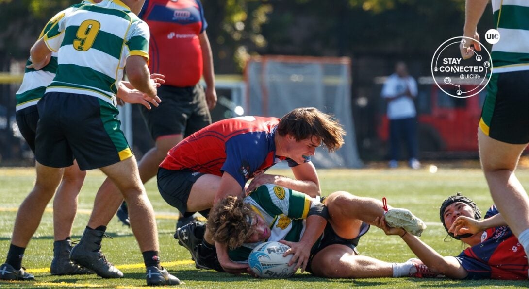 Men huddled around a rugby ball at a UIC home game.