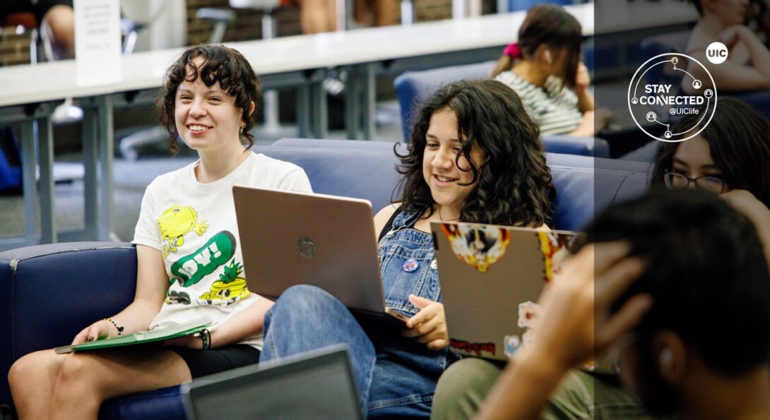 Students smiling while working on their laptops in the Commuter Student Resource Center.